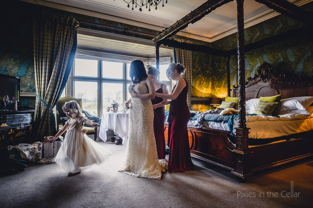 bridesmaids helping bride into wedding dress