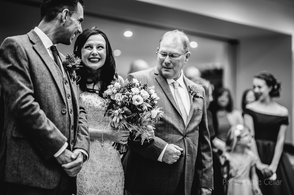 groom bride and dad smiles at end of aisle